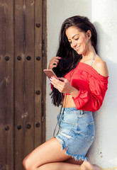 Fototapeta premium Close up portrait of a young woman using a smartphone to listen to music with her head phones