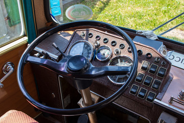 driver's seat of a vintage bus. Black steering wheel and driving controls