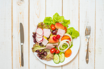 Vegetables salad on dish on white wood table