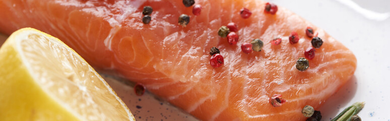 close up view of raw salmon steak with peppercorns and lemon, panoramic shot
