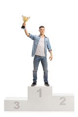 Young boy holding a gold trophy cup on a winner pedestal