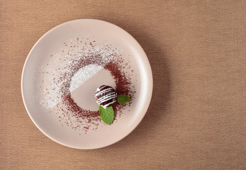 Chocolate ball with mint on a beige plate.
