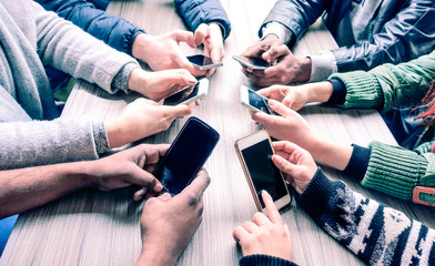 Group of friends using phone around meeting table - Multiracial people hands holding smartphone sitting in circle -  Technology and lifestyle concept- Image