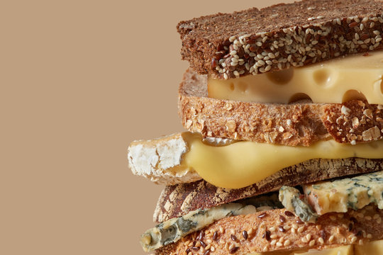 Fresh cheese and slices of organic homemade bread with sesame and flax seeds is a healthy sandwich on a brown background with space for text. Macro photo