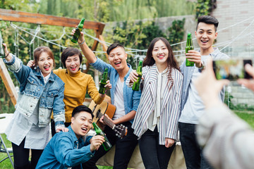 Girl taking photo of group friends at a backyard party