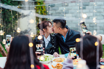 Young couple kissing in a backyard dinning party