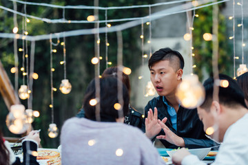 Group of friends having dinner together in a backyard