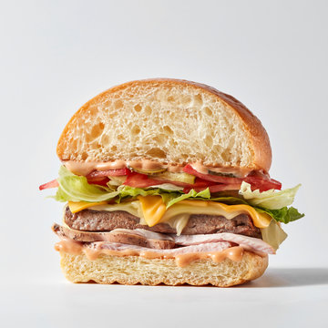 Half of homemade burger with tasty beef cutlet, ham, fresh veget