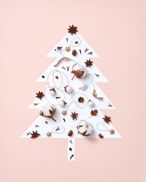 Christmas composition of dry leaves, pine cones, anise and paper stars in the shape of a Christmas tree on a beige-gray background with copy space. Postcard. Flat lay