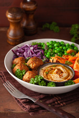 healthy vegan lunch bowl with falafel hummus carrot ribbons cabbage and peas