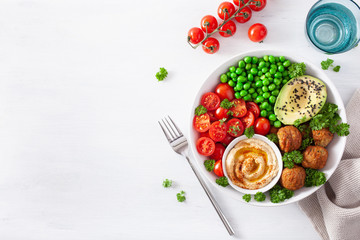 healthy vegan lunch bowl with falafel hummus tomato avocado peas