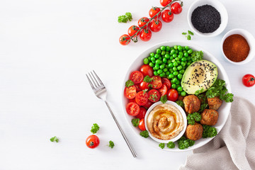 healthy vegan lunch bowl with falafel hummus tomato avocado peas