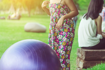 Happiness girl in the floral skirt relax and play with a big ball on green field in the public...