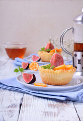 Grated mini pie with cottage cheese topped with pieces of figs and kumquats on ceramic plate