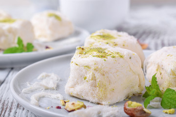 Cotton candy with pistachio on ceramic plate on white wooden table