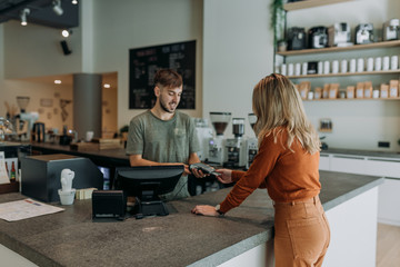 blonde woman paying in a cafe