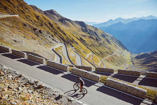 Road cyclist going uphill in alps.