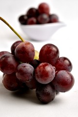 Bunch of grapes, in the background in a ceramic utensil grapes inside, the background is diffuse