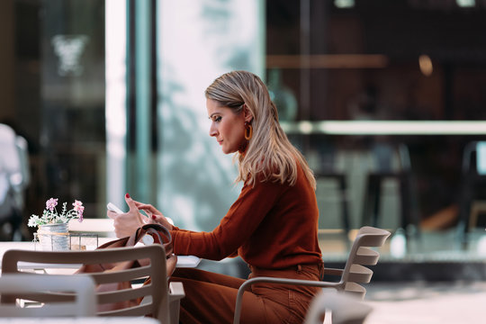Woman with autumn outfit working inside coffee bar.