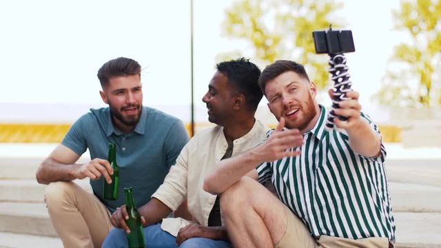 leisure, technology and people concept - happy male friends taking selfie by smartphone and drinking beer at rooftop party in summer