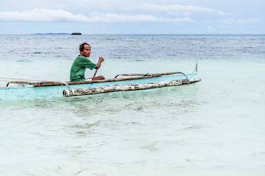 Asian man sitting on boat and rowing