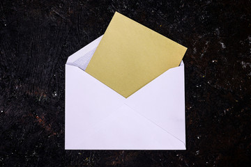 Envelope mock up. White open envelope with a yellow vintage card inside on dark background.