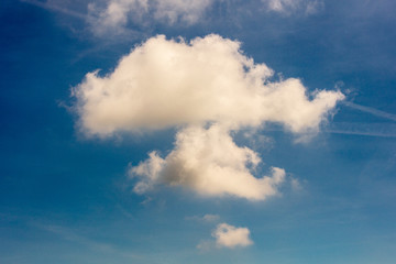 Naklejka na ściany i meble A puffy white cloud in a blue sky