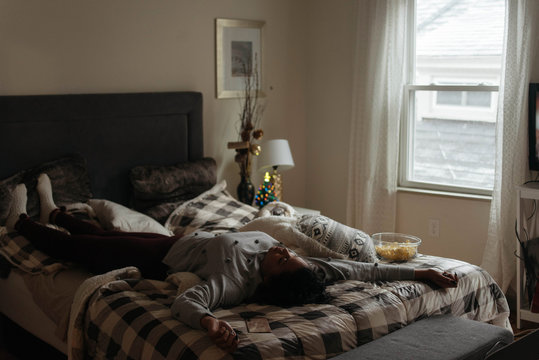 A woman watching television and eating popcorn at christmas time