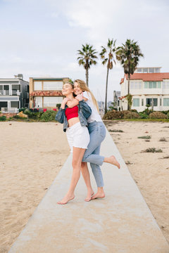 Sisters holding each other in front of their beach home