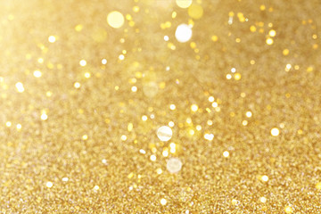 Gold festive glitter background with bokeh golden lights.