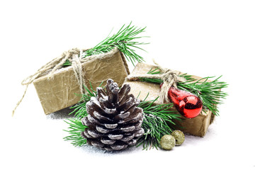 Snowy spruce branch with fir cones and gift box isolated on white background.