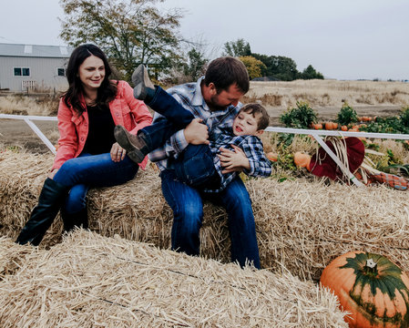 family rides in hay wagon with pumpkins