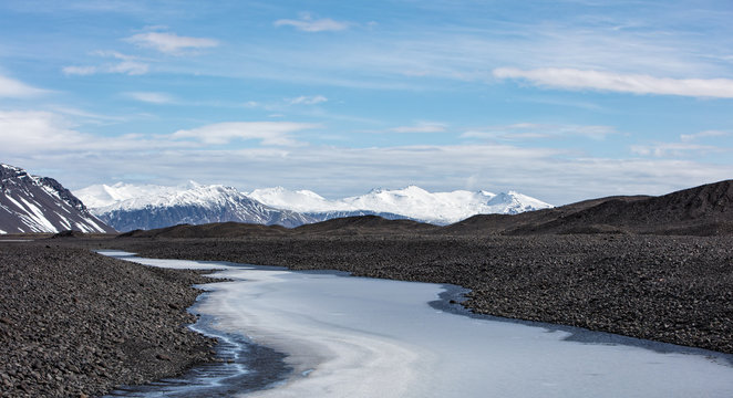 A meltwater river from a glacier flowing towards mountains.