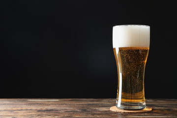 Mag with beer on wooden table, space for text