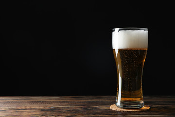 Mag with beer on wooden table, space for text