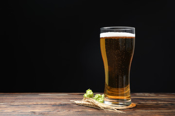 Mag with beer, spikelets and hop on wooden table, space for text