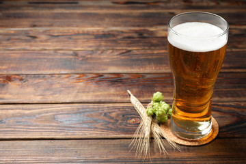 Mag with beer, spikelets and hop on wooden table, space for text