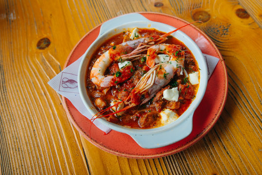 Greek traditional food. Oven backed prawns with feta, tomato, paprika, thyme in a traditional ceramic form on a abstract background. Healthy eating concept. Mediterranean lifestyle.