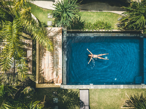 aerial view of young woman floating in a pool in a tropical resort