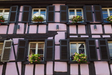 Fototapeta premium Colorful wall of old half-timbered house with multiple windows and wooden shutters