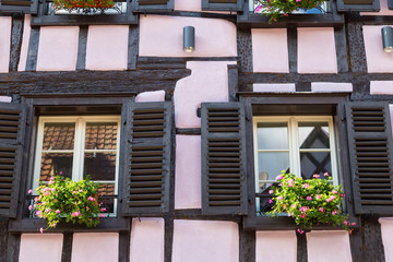 Colorful wall of old half-timbered house with multiple windows and wooden shutters