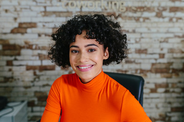 Smiling bright woman at desk in office