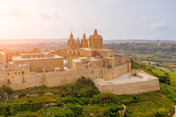 St. Paul's Cathedral in the town of Mdina surrounded by a fortress narrow streets, aerial view.