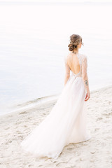 Fototapeta na wymiar Bride walking along sea coast in the wedding dress