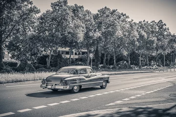 Fotobehang Zwart-wit zwart-wit foto van een Amerikaanse oldtimer auto uit de jaren 50. Vintage USA auto op straat op een zonnige zomerdag. Retro reizen, verkeersconcept. © Gaschwald