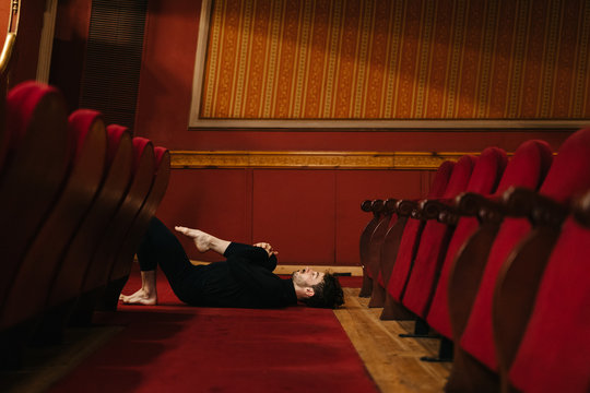 Male dancer stretching on theatre floor