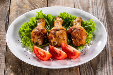 Fried chicken drumsticks with vegetables on wooden table