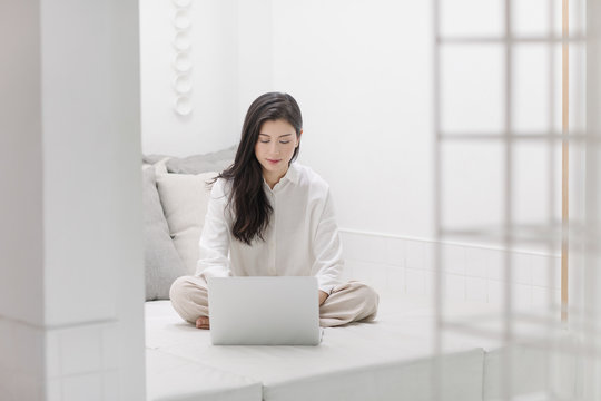 A Woman Sitting on a Bed and Using Laptop