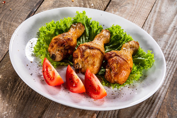 Fried chicken drumsticks with vegetables on wooden table