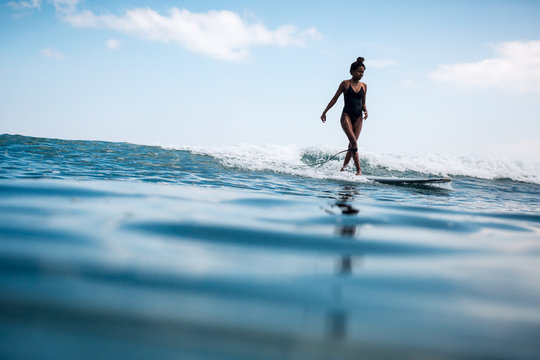 Young indonesian woman on a surf board in the ocean
